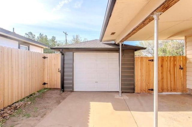 garage with fence, a gate, and driveway