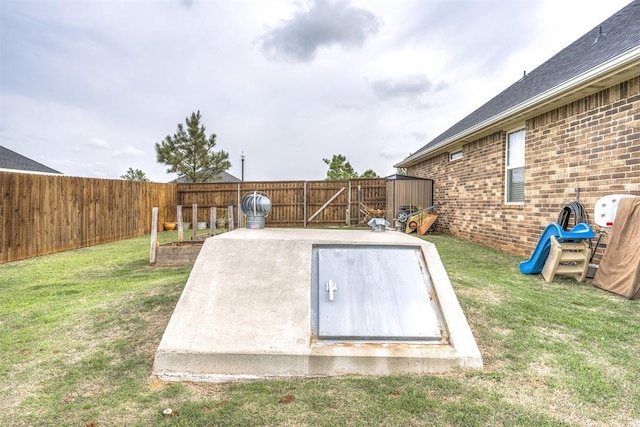 entry to storm shelter with a lawn and a fenced backyard