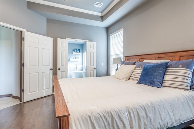bedroom with crown molding, visible vents, wood finished floors, and ensuite bath