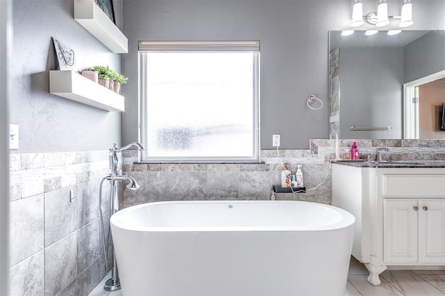 full bath with tile walls, a soaking tub, and vanity