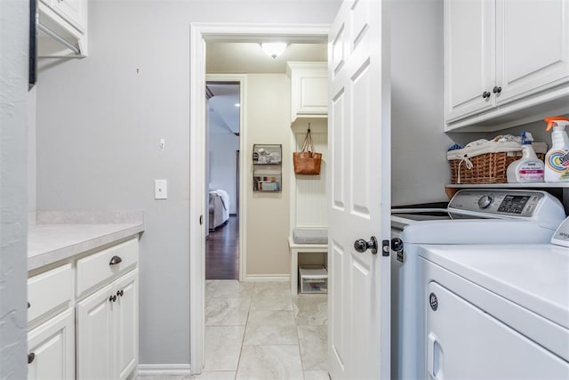 clothes washing area featuring baseboards, cabinet space, and independent washer and dryer
