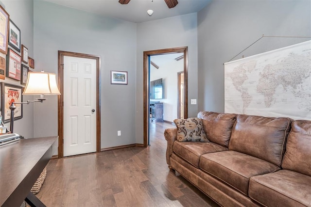 living area featuring baseboards, a ceiling fan, and wood finished floors