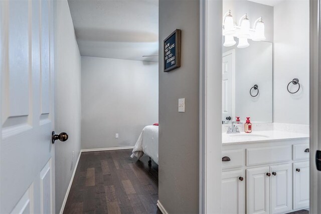 bathroom featuring baseboards, an inviting chandelier, wood finished floors, and vanity