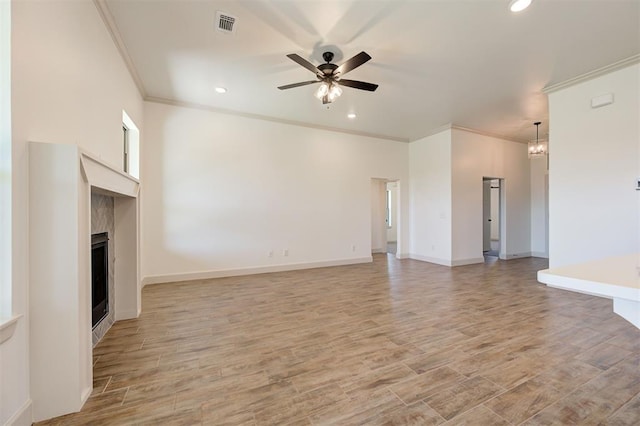 unfurnished living room featuring crown molding, visible vents, a fireplace, light wood-style floors, and ceiling fan