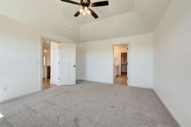unfurnished bedroom featuring baseboards, ensuite bathroom, vaulted ceiling, and light colored carpet