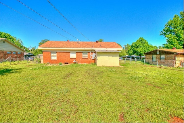 back of house featuring brick siding, fence, and a yard