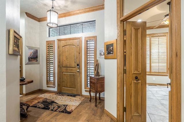 entryway with a ceiling fan, baseboards, ornamental molding, and a towering ceiling