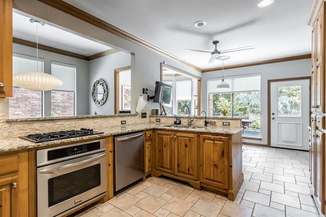 kitchen featuring brown cabinetry, a ceiling fan, pendant lighting, a sink, and stainless steel appliances