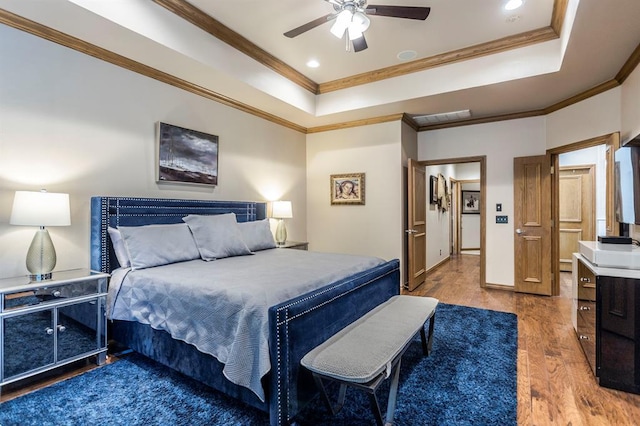 bedroom featuring crown molding, recessed lighting, wood finished floors, and a tray ceiling
