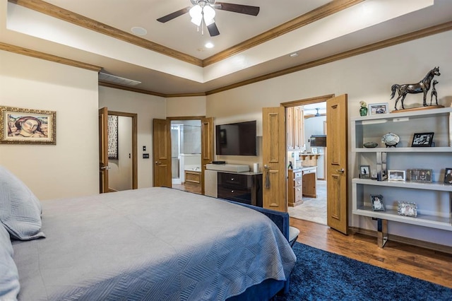 bedroom with ornamental molding, wood finished floors, recessed lighting, a tray ceiling, and ensuite bath