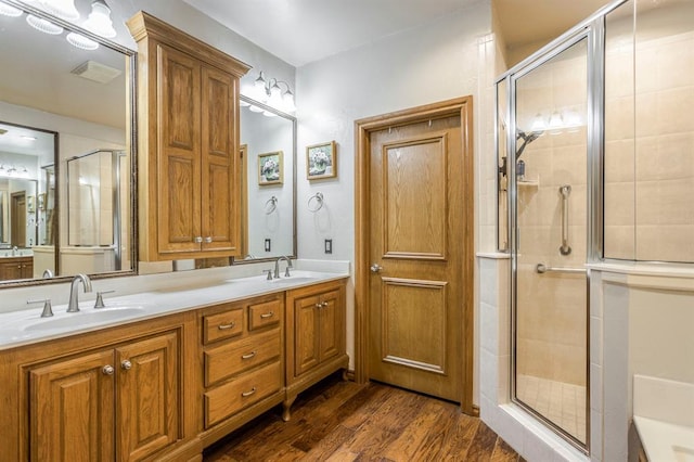bathroom with a sink, double vanity, a stall shower, and wood finished floors
