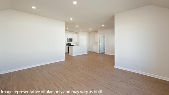 unfurnished living room featuring recessed lighting, baseboards, wood finished floors, and lofted ceiling