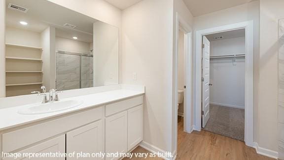 full bathroom featuring vanity, baseboards, wood finished floors, visible vents, and a stall shower