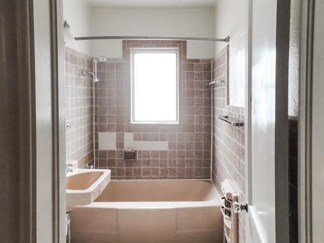 full bath featuring a sink, tile walls, and  shower combination