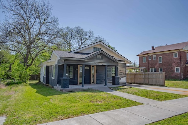 view of front of property featuring a front lawn, fence, and covered porch