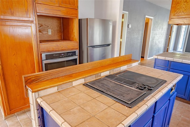 kitchen featuring tile countertops, appliances with stainless steel finishes, and blue cabinets