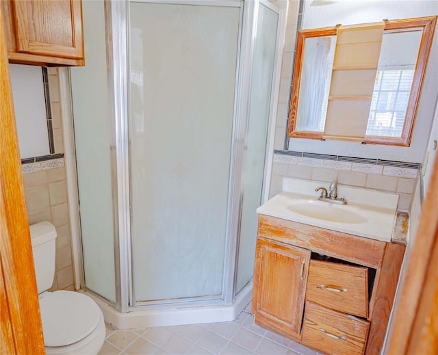 bathroom with vanity, toilet, tile patterned floors, tile walls, and a shower stall