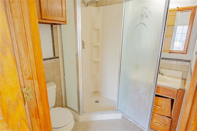 bathroom featuring tile patterned floors, a shower stall, toilet, and tile walls
