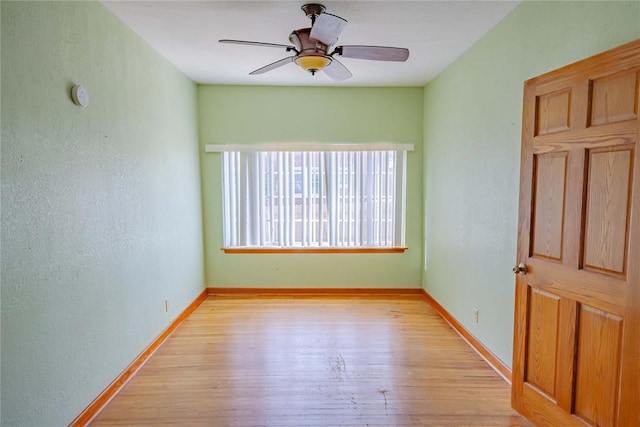 unfurnished room featuring a ceiling fan, baseboards, and light wood-type flooring