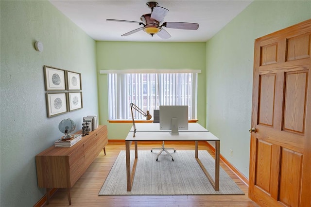 office space featuring baseboards, a ceiling fan, light wood finished floors, and a textured wall