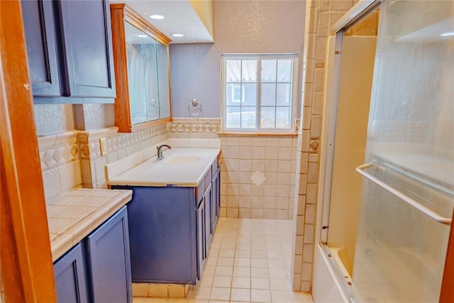 full bathroom featuring tile patterned floors, tile walls, wainscoting, and vanity