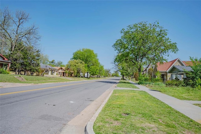 view of road with a residential view, sidewalks, and curbs