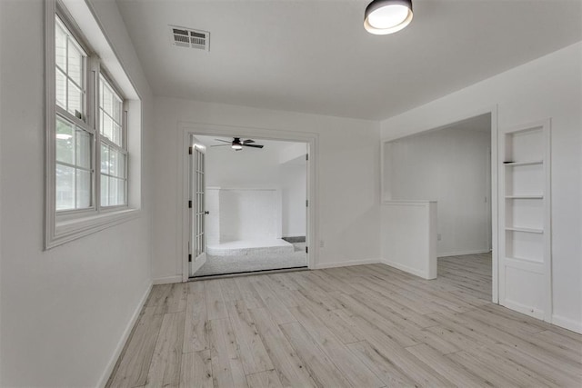 empty room featuring baseboards, ceiling fan, light wood-type flooring, and visible vents