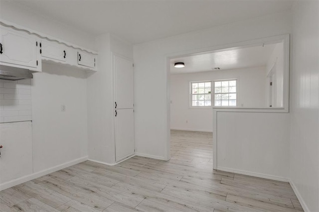 empty room with baseboards, light wood finished floors, and visible vents