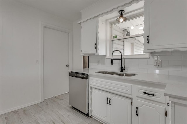 kitchen with dishwashing machine, decorative backsplash, a sink, and white cabinets