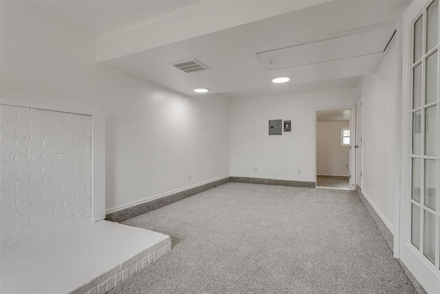 spare room with electric panel, attic access, visible vents, carpet floors, and baseboards