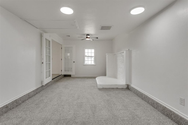 unfurnished room with a ceiling fan, attic access, visible vents, baseboards, and carpet