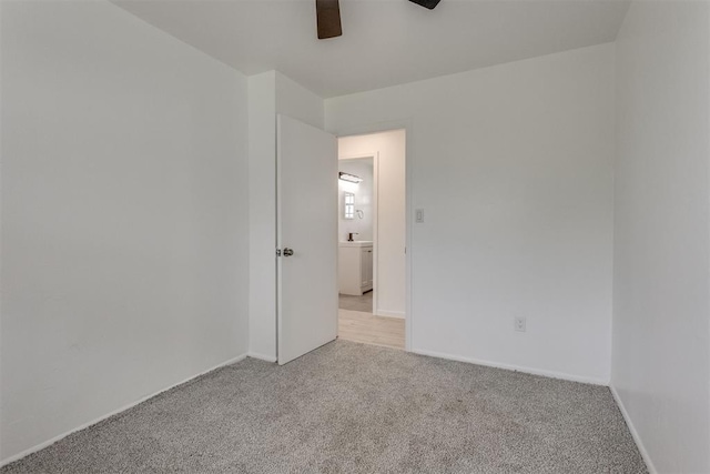spare room featuring light colored carpet, a ceiling fan, and baseboards