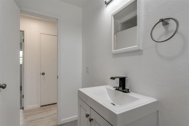 bathroom with baseboards, wood finished floors, and vanity