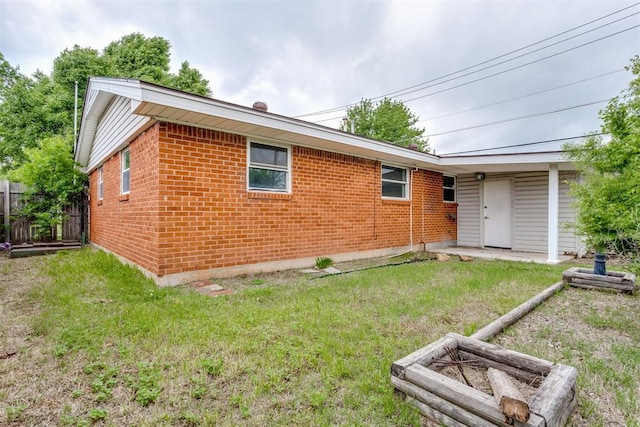 back of property with a lawn, brick siding, and fence