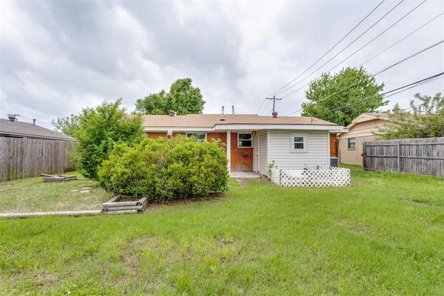 back of house with a lawn, fence, and brick siding