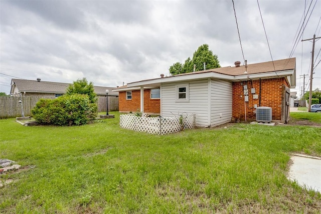 rear view of property with brick siding, fence, and a yard