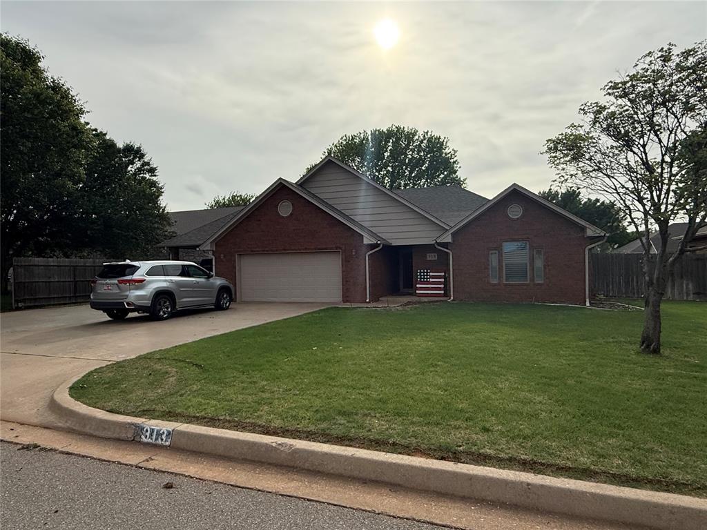 ranch-style home with fence, brick siding, a garage, a front yard, and concrete driveway