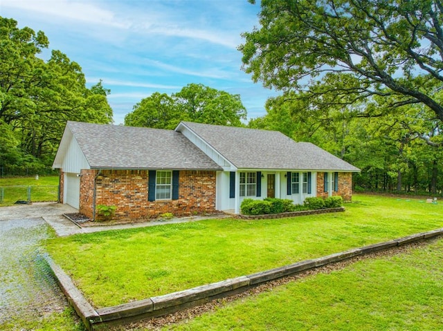 ranch-style home featuring fence, a front lawn, brick siding, roof with shingles, and gravel driveway
