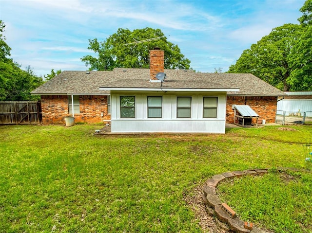 rear view of property with a chimney, a yard, brick siding, and a fenced backyard