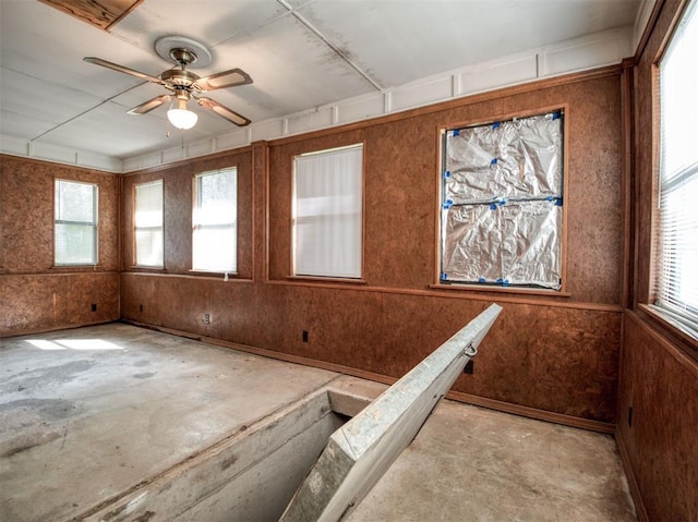 unfurnished room featuring plenty of natural light, unfinished concrete floors, and ceiling fan