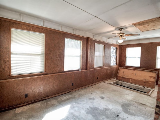 spare room featuring unfinished concrete floors and ceiling fan