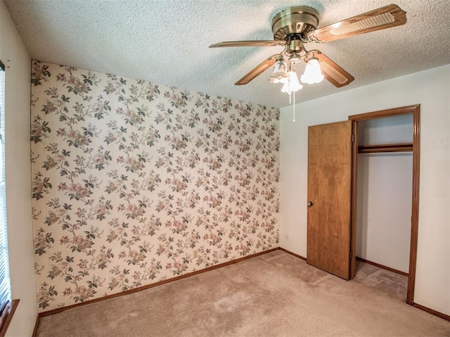 unfurnished bedroom with a textured ceiling, a closet, ceiling fan, and light colored carpet