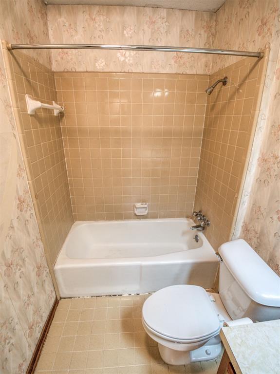 bathroom with vanity, toilet, bathtub / shower combination, and wallpapered walls