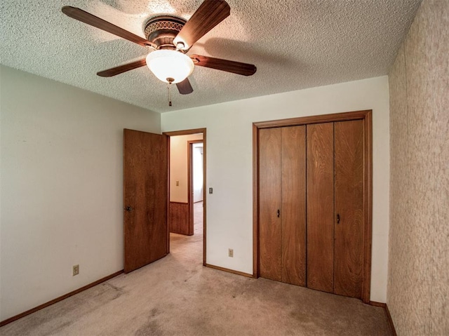 unfurnished bedroom featuring light carpet, a textured ceiling, a closet, and a ceiling fan