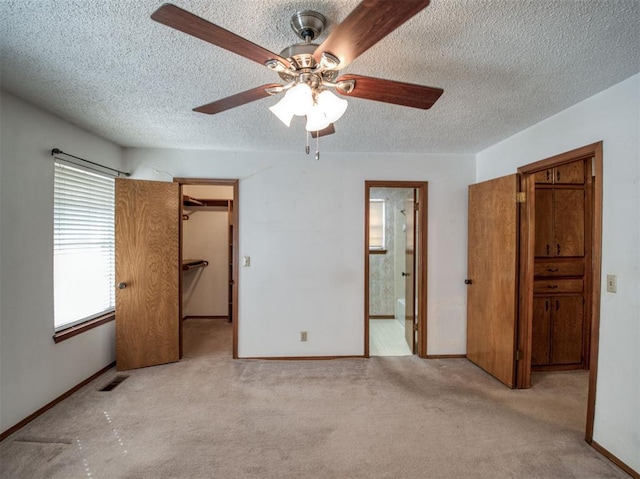 unfurnished bedroom featuring carpet flooring, a textured ceiling, visible vents, baseboards, and a spacious closet