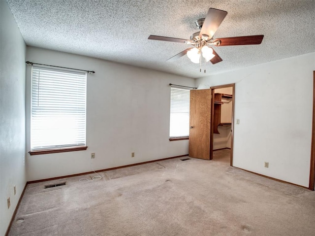 unfurnished bedroom with baseboards, light carpet, visible vents, and a textured ceiling