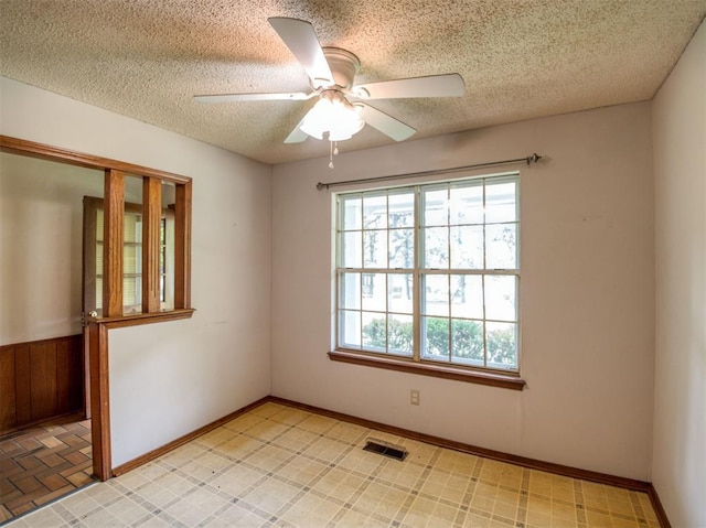 spare room with a textured ceiling, visible vents, and ceiling fan