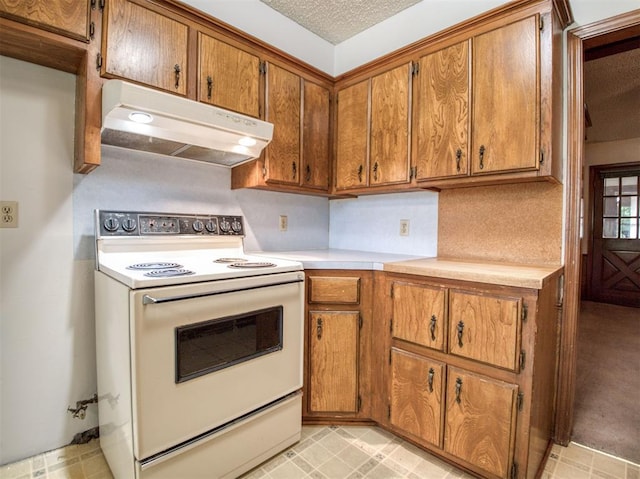 kitchen featuring under cabinet range hood, white range with electric stovetop, light countertops, and brown cabinets