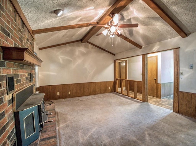 interior space featuring lofted ceiling with beams, a textured ceiling, wood walls, wainscoting, and ceiling fan