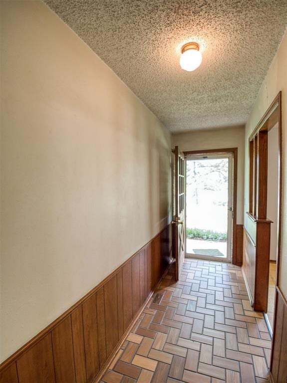 hall with wooden walls, wainscoting, and a textured ceiling